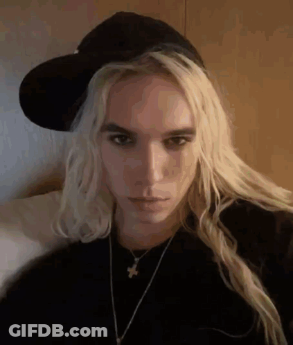 Woman With Long Blonde Hair Wearing Hat And Necklace GIF