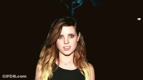 Woman With Long Brown Hair Smiling In Dark Room GIF