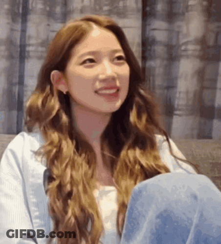Woman With Long Brown Hair Smiling On Couch GIF
