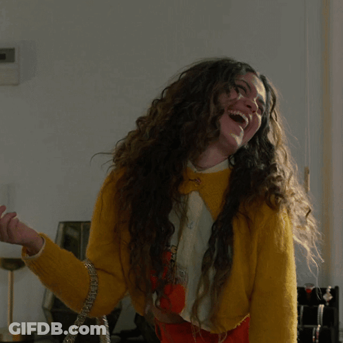 Woman With Long Curly Hair In Yellow Sweater And Orange Skirt GIF