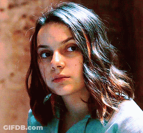Woman With Long Dark Hair In Blue Shirt Looking At Camera GIF