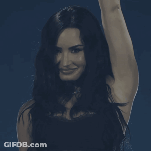 Woman With Long Dark Hair Smiling Hand In Air GIF