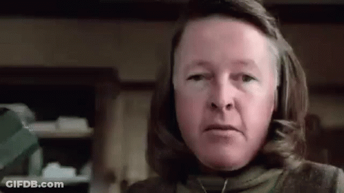 Woman With Long Hair And Necklace Looking At Camera In Kitchen GIF