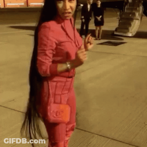 Woman With Long Hair In Pink Suit Holding Red Bag GIF