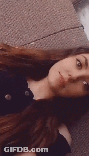 Woman With Long Hair Laying On Couch Making Face GIF
