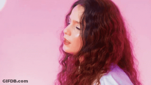 Woman With Long Red Curly Hair In Front Of Pink Wall GIF