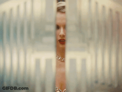 Woman With Necklace And Earrings Looking Through Glass Door GIF