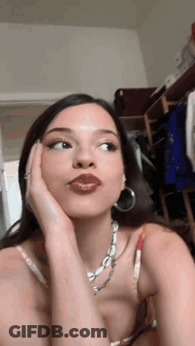 Woman With Necklace And Hoop Earrings Looking At Camera GIF