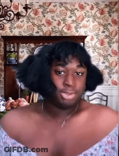 Woman With Necklace And Wig Before Floral Wallpaper GIF