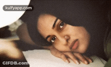 Woman With Nose Ring Lying On Bed Head On Hand GIF