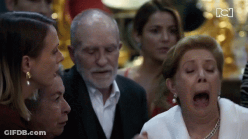 Woman With Open Mouth Surrounded By Group Including Elderly Man GIF