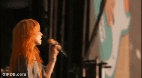 Woman With Orange Hair Singing Into Microphone GIF