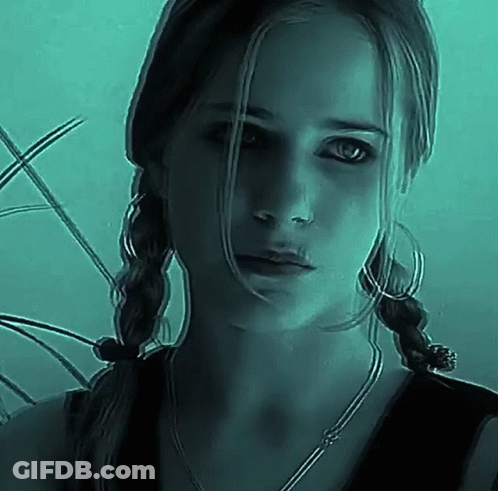 Woman With Pigtails And Hoop Earrings Looking At Camera In Dark Room GIF