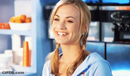 Woman With Pigtails Smiling In Front Of Blue Shelf GIF