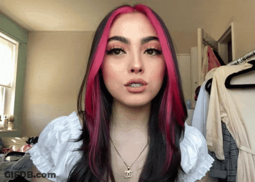 Woman With Pink And Black Hair Wearing Necklace With Letter C GIF