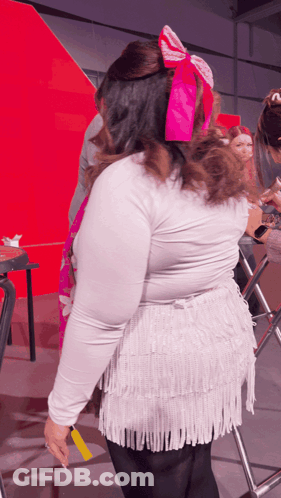 Woman With Pink Bow In Hair In Front Of Red Wall GIF