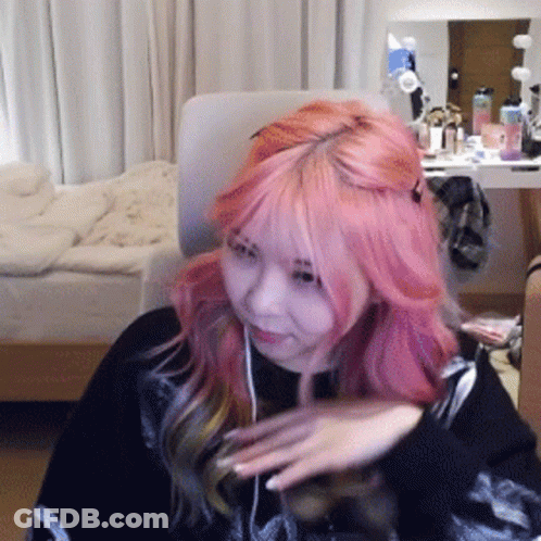 Woman With Pink Hair Sitting In Front Of Bed GIF
