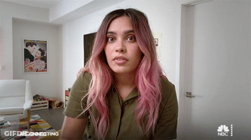 Woman With Pink Hair Sitting In Living Room With NBC Logo GIF