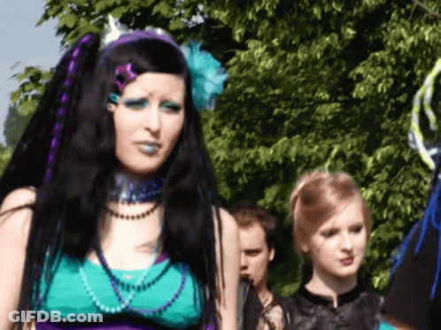 Woman With Purple Hair And Blue Makeup In Front Of Tree GIF