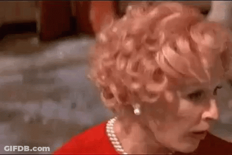 Woman With Red Curly Hair And Pearl Necklace Looking At Camera GIF