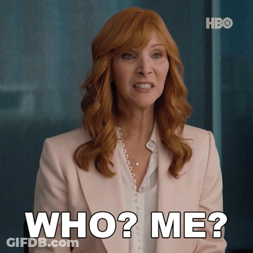 Woman With Red Hair And Pink Jacket Saying Who Me GIF