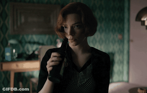 Woman With Red Hair Holding Bottle In Dark Room GIF