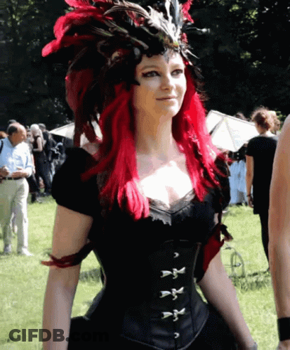 Woman With Red Hair In Black Corset And Feathered Headdress GIF