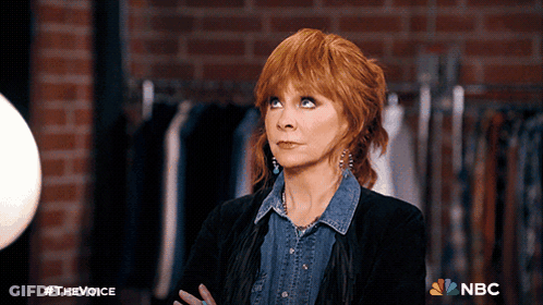 Woman With Red Hair In Front Of Brick Wall With NBC Logo GIF