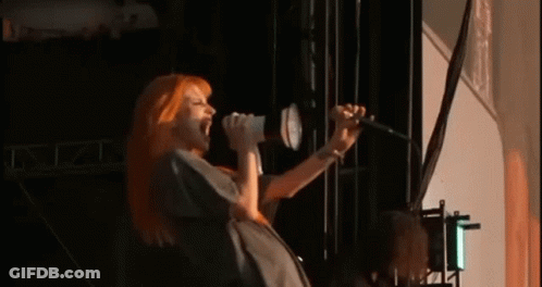 Woman With Red Hair Singing Into Microphone GIF