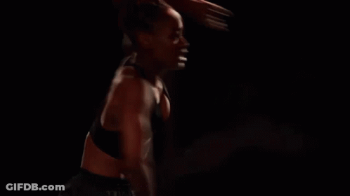 Woman With Red Hair Standing In Dark Room Arms Outstretched GIF