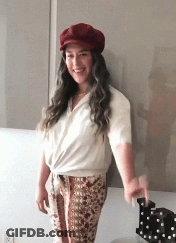 Woman With Red Hat And White Shirt Standing By Wall GIF