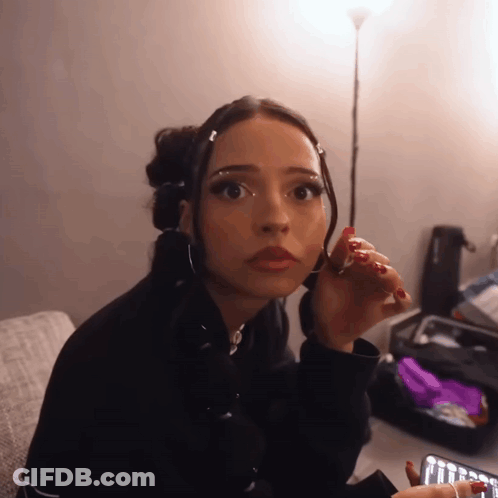 Woman With Red Nails Sitting On Couch Looking At Camera GIF