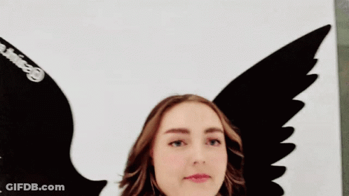 Woman With Scarf Standing In Front Of Bird Wings Painting GIF