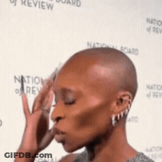 Woman With Shaved Head In Front Of Wall GIF