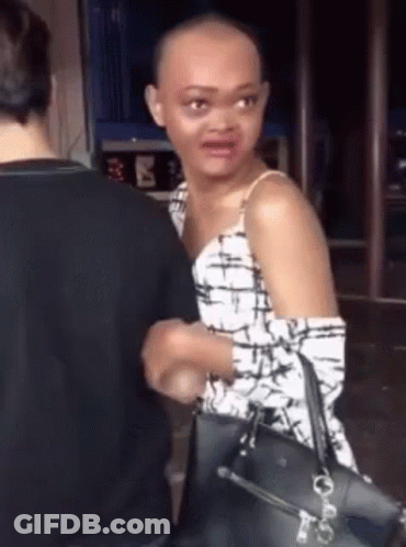 Woman With Shaved Head Standing Next To Man Holding Purse GIF
