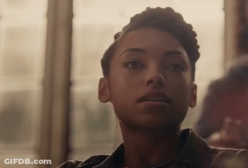 Woman With Short Hair Sitting In Front Of Window Looking At Camera GIF