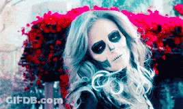 Woman With Skeleton Makeup Sitting In Front Of Flowers GIF
