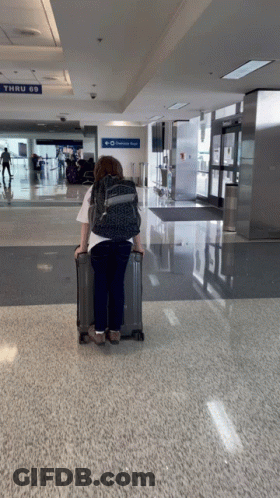 Woman With Suitcase At Airport Thru 69 Sign GIF