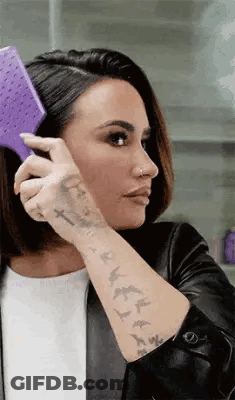 Woman With Tattoos Brushing Hair With Purple Brush GIF