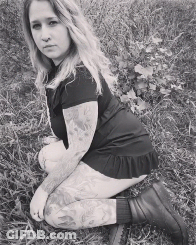 Woman With Tattoos Kneeling In Grass GIF