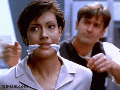 Woman With Tie Around Mouth Looking At Camera GIF