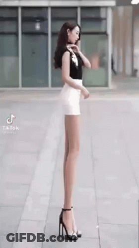 Woman With Very Long Legs On Sidewalk In Heels GIF