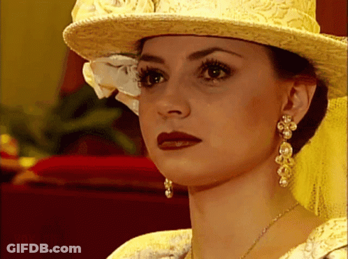 Woman Yellow Hat Pearl Earrings Looking At Camera GIF