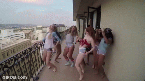 Women Dancing On Balcony Overlooking City GIF