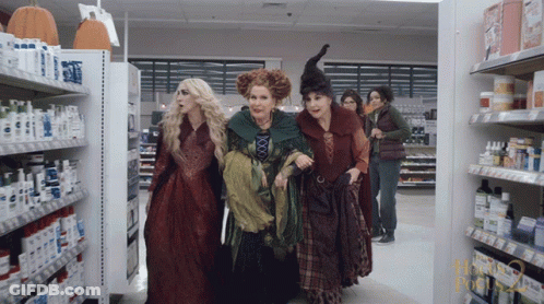 Women Dressed As Witches Walk Through Pharmacy GIF