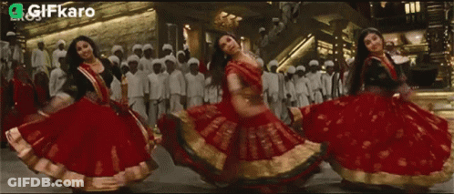 Women In Red And Gold Dresses Dancing With Gifkaro Logo GIF