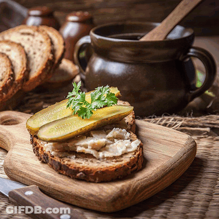 Wooden Cutting Board With Sandwich And Pickles GIF