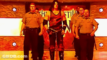 Wrestler Chained To Wall Surrounded By Security Guards GIF