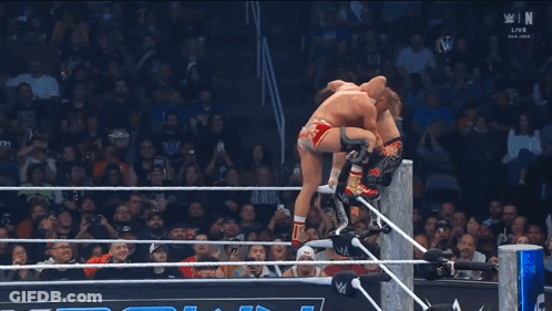 Wrestler Falling Through Ring While Referee Watches GIF
