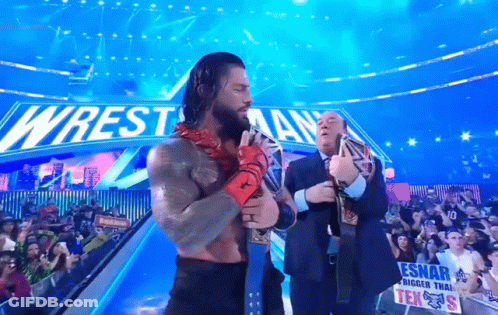 Wrestler Holding Belt In Front Of Wrestlemania Sign GIF